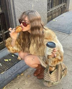 a woman sitting on a bench eating food and holding a coffee cup in her hand