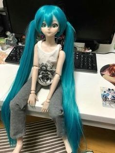 a doll sitting on top of a desk next to a computer