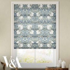 the roman blind in blue with white flowers on it is next to a window sill