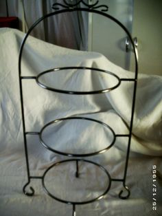 a bed with a white sheet and a metal rack on top of it that is holding two round trays