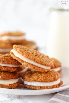 cookies with icing and marshmallows on a plate next to a bottle of milk