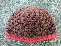 a brown and red knitted hat laying on the ground