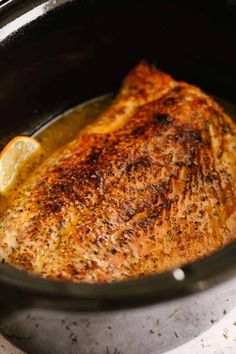 a piece of fish in a pot with lemon wedges