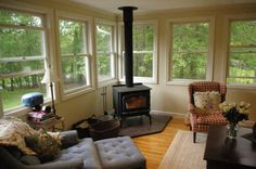 a living room with couches and a wood burning stove in the middle of it