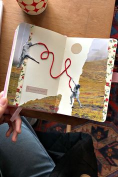 a person holding an open book with scissors in it