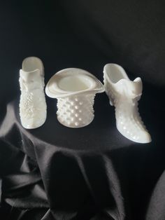 three white vases sitting on top of a black cloth