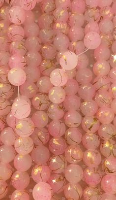 many pink and gold balloons are in the shape of balls with sparkles on them