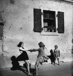 an old black and white photo of children playing with each other in front of a building