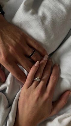 two hands holding each other on top of a white sheet with one hand wrapped around the other