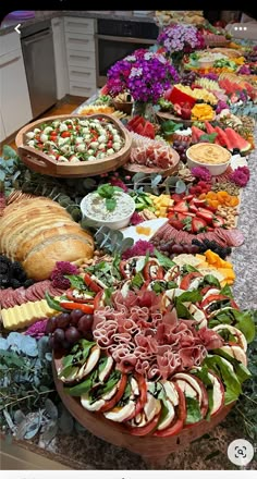 an assortment of food is displayed on a long table with breads and salads