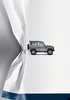 a jeep is parked on the side of a white wall with blue stripes and an advertisement for land rover