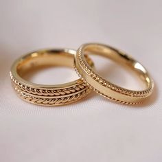 two gold wedding rings sitting on top of each other