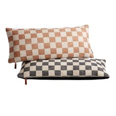 two pillows sitting on top of each other in front of a white background and brown checkerboard pattern