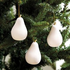 three white ornaments hanging from a christmas tree