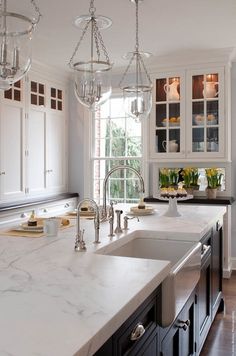 a kitchen with marble counter tops and white cabinets, along with an island in the middle