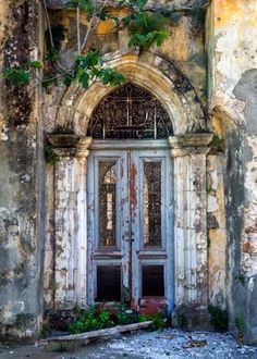 an old building with two doors and ivy growing on it