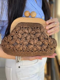 a woman holding a brown crocheted purse