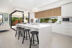 a kitchen with white counter tops and stools next to an island in the middle