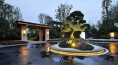 an outdoor fountain in the middle of a park at night with lights on and trees lit up