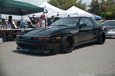 a black sports car parked in front of some tents