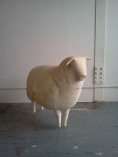 a sculpture of a sheep standing in front of a white wall