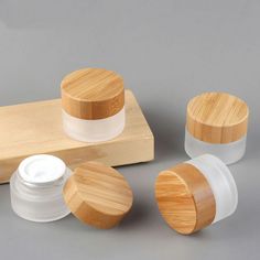 three wooden containers and one white container are sitting on a gray surface next to each other