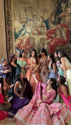 a group of women standing next to each other in front of a tapestry