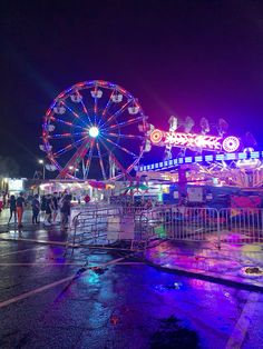 an amusement park at night with ferris wheel and carnival rides in the background on wet pavement