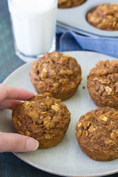 a person picking up some muffins from a plate