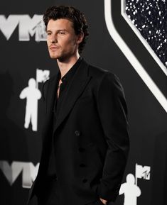 a man in a black suit standing on a red carpet