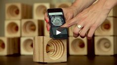 a woman holding an iphone in front of stacks of wooden blocks with images on them