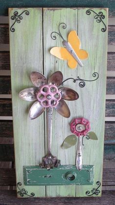 a wooden sign with metal flowers and butterflies on it's side, attached to a wall