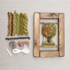 a wooden frame with yarn, scissors and other crafting supplies laid out on a table