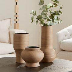 three vases with plants in them sitting on a table next to a couch and chair