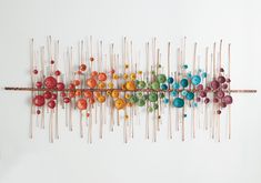 a group of pins sitting on top of a wooden stick next to a white wall