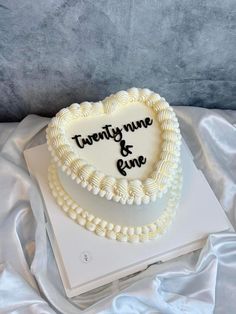 a heart shaped cake with the words twenty nine and nine on it sitting on top of a white sheet