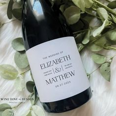 a bottle of wine sitting on top of a table next to some leaves and flowers