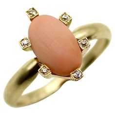 This pale pink coral cabochon is elegant and feminine, circa the Victorian era, and set on a 14k gold ring. The coral has a beautiful matte surface with delicate wood-like graining. The cabochon is surrounded by six Old Mine Cut diamonds, sweetly framed in square mounts. Part of our signature collection, this piece was once a stickpin. We had our jeweler remove the pin and mount a ring shank to the coral. It now makes a gorgeous conversion piece. Stickpins rose to prominence in the early and mid 1800’s; it was customary for upper class men to wear them to secure their ties and cravats. Pins were also worn on the lapels of coats, and incorporated into hats. Eventually, women took interest in wearing stickpins and began using them on scarves. The Old Mine Cut diamonds are 1 mm each, with bea Luxury Heirloom Cabochon Jewelry, Elegant Oval Coral Rings, Elegant Coral Oval Rings, Victorian Ring, The Victorian Era, Ring Shank, Victorian Rings, Pink Coral, 14k Gold Ring