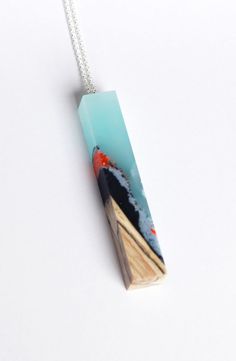 a piece of wood is hanging from a chain on a white surface with an orange and blue design