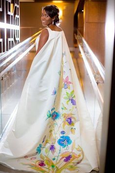 a woman in a white dress is standing on the escalator and looking off into the distance