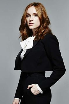 a woman with red hair wearing a black suit and white bow tie posing for the camera