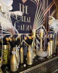 a table topped with gold vases filled with feathers and other decorative items on top of it