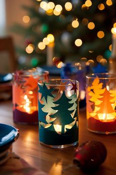 three lit candles sitting on top of a wooden table next to a christmas tree in the background