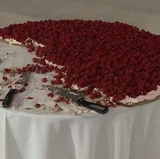 there is a cake that has been cut into pieces and placed on a table with knifes