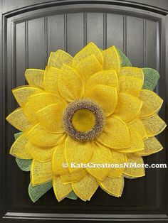 a yellow mesh sunflower wreath on a black door with the words kate creations above it