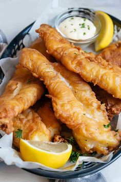 a basket filled with fried fish and lemon wedges