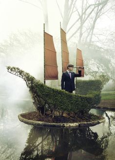 a man in a suit and tie standing on top of a boat with two sails