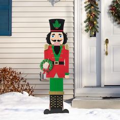 a wooden nutcracker standing in front of a house with christmas wreaths on the door