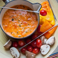 a bowl filled with soup next to some vegetables and mushrooms on a plate, ready to be eaten