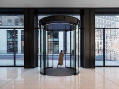 a woman standing in front of a revolving glass door at the entrance to a building